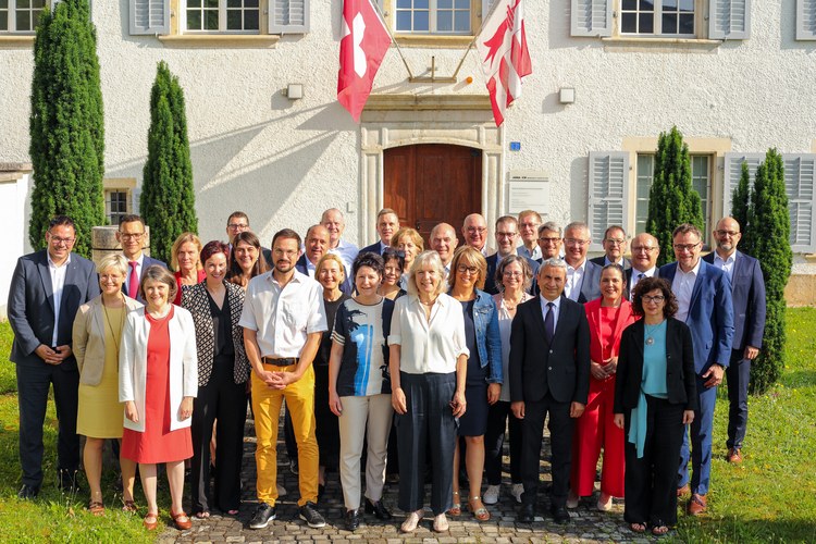 Photo de la conférence plénière 2025 - représentants gouvernementaux des 7 cantons membres devant l'Hôtel du Parlement jurassien (JU)