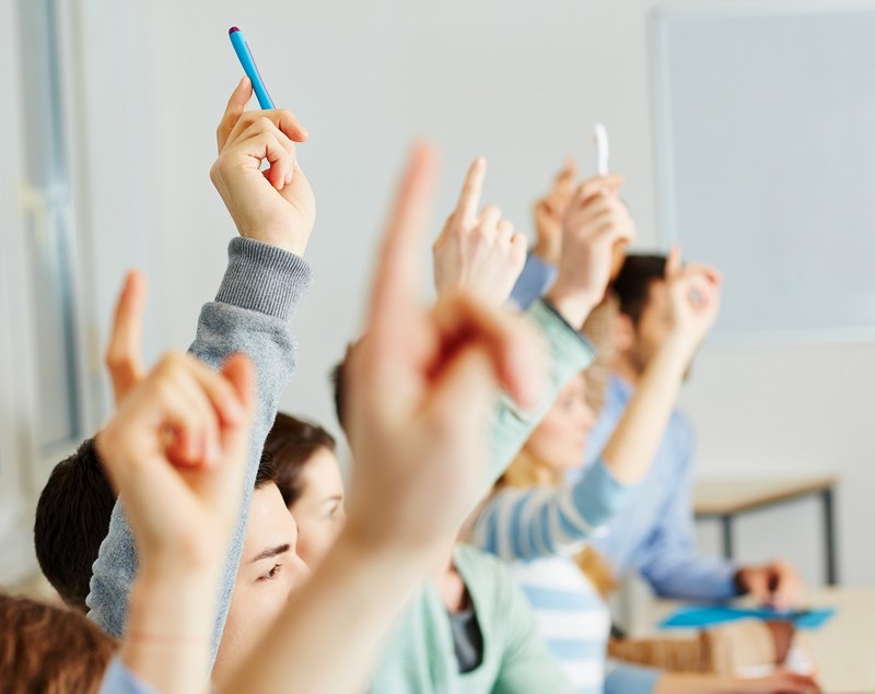 Sekundarschülerinnen und Schüler zeigen im Unterricht auf
