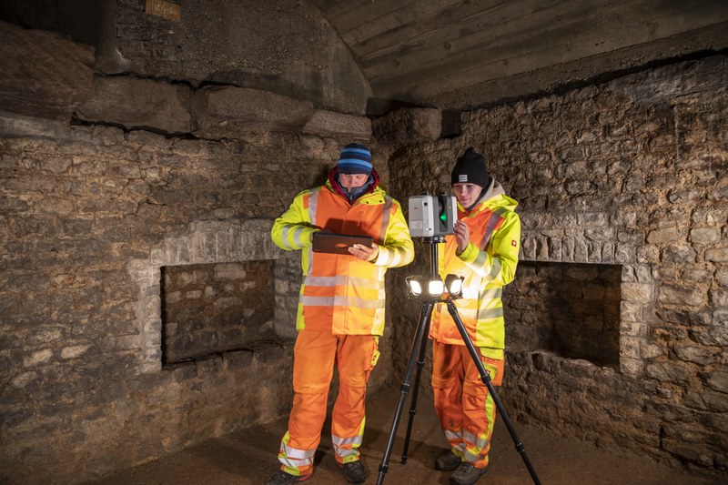 Zwei Geometer bei der Arbeit mit dem 3D-Scanner im römischen Keller