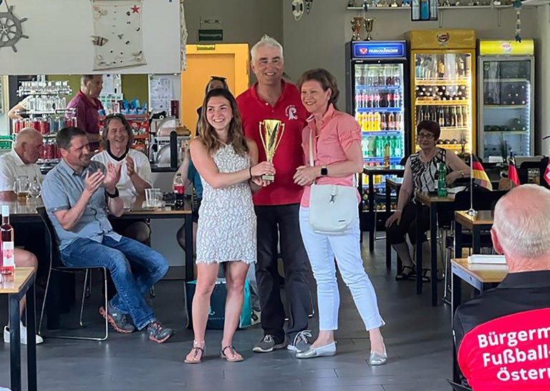 Der Präsident des FC Landrat, Andreas Bammatter, übergibt den Pokal für den Sieg am Jubiläumsturnier an die Kreis-Kicker Lörrach, vertreten durch Captain Laura Bastian (l.) und Landrätin Marion Dammann.